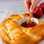 Baked round challah with a bowl of honey in the center